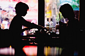 Silhouette von zwei jungen Frauen am Tisch in einem Cafe