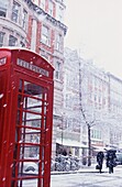 Schneefall auf einer roten Telefonzelle auf dem Marktplatz