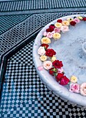 Marokko, Nahaufnahme; Marrakesch, Blumenblüten schwimmen in Springbrunnen auf dem gefliesten Boden