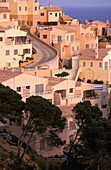 Curved Road Going Down Hilltop Village By Coastline