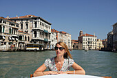 Frau fährt auf einem Wassertaxi in Venedig, Canal Grande