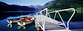 Ruderboote am Steg auf dem See zwischen Bergen
