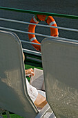 Eine Frau entspannt sich in einem Stuhl und liest ein Buch an Bord einer Flusskreuzfahrt