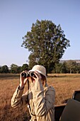 Frau auf Safari schaut durch ein Fernglas