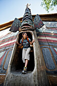 Frau erkundet das Clan-Haus im Totem Bight State Historical Park in der Nähe von Ketchikan, Südost-Alaska, Sommer