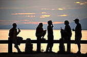 Eine Gruppe von Freunden beobachtet gemeinsam den Sonnenuntergang am Point Woronzof in Anchorage, Süd-Zentral-Alaska, Sommer/N