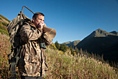 Männlicher Elchjäger benutzt einen Elchruf, um Elche zu rufen, Bird Creek Drainage Area, Chugach Mountains, Chugach National Forest, Southcentral Alaska, Herbst
