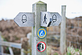 A wooden post and directional signs for walking paths; Wales