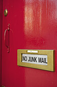 Ein Schild an einem Briefschlitz an einer roten Tür mit der Aufschrift "No Junk Mail"; London, England