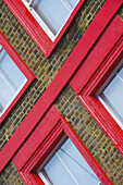 Leuchtend rote Umrandung von Fenstern an einem Backsteingebäude; London, England