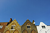 Fassade von Wohngebäuden mit spitzen Dächern und blauem Himmel, Camden; London, England