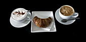 Kaffee und Croissant auf einem schwarzen Hintergrund