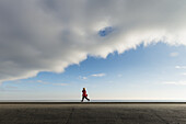 Junge läuft entlang des Deichs; Aldeburgh, Suffolk, England