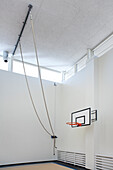 Indoor sports hall in a school, climbing ropes attached to the ceiling. 
