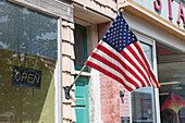 American flag in front of a building, a shop window on main street. 
