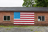 An American flag painted on empty building on a street in a small town.