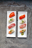 A sushi platter with fresh fish and rice arranged carefully on the dish with garnishes. 