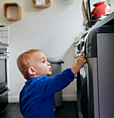 close up of toddler reaching up and touching appliance in kitchen