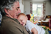 Close up of laughing toddler in arms of grandfather