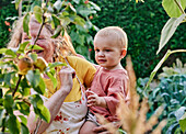 Grandmother holding toddler on hip in garden