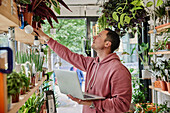Man stock-taking using laptop in flower shop
