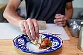 Ein Mann bereitet Essen in einem Restaurant zu, er legt Gemüse und Pastete auf einen Teller. Nahaufnahme.