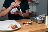 Ein Koch bereitet in einem Restaurant italienische Gerichte zu. Er verwendet einen Schweißbrenner, um ein Gericht zu erhitzen.