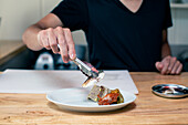 Ein Koch bereitet in einem Restaurant Teller mit Tapas zu.