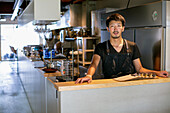 A man standing at the counter of a restaurant kitchen, the owner or manager. 