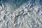 The surface of churning ocean water, overhead view.