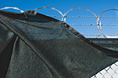 A barbed wire fence and draped fabric.