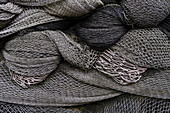 Ein Haufen kommerzieller Fischernetze, graue Netze, die zusammengefaltet sind. 