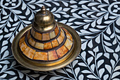 Morocco, Fes. A covered brass bowl with inlay of camel bone sites on a stone inlay table in a shop.