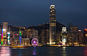 Hong Kong, China. Skyline harbor with new Ferris Wheel and reflections on water and mountain peak in background