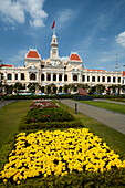 Blumen und historisches Gebäude des Volkskomitees (ehemaliges Hotel de Ville de Saigon), Ho-Chi-Minh-Stadt (Saigon), Vietnam