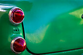 Detail of two red tail lights on classic green car in Trinidad, Cuba