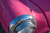 Detail of chrome head light on hot pink classic American Oldsmobile in Vieja, old Habana, Havana, Cuba.