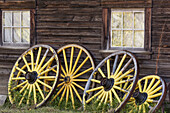 Canada, British Columbia, Barkerville. Wagon wheels lean on old building
