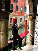 Venice, Italy. Gondolier man looks out onto the canal next to his gondola