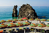 Beach umbrellas lining the beach in Monterosso al Mare, Cinque Terre, Italy.