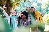 Happy friends taking selfie with smartphone in public park