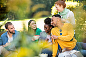 Fröhliche junge Freunde beim Picknick in einem öffentlichen Park