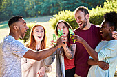 Glückliche junge Freunde stoßen mit Bierflaschen im Garten an