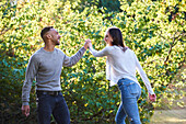 Lächelndes junges Paar tanzt in einem öffentlichen Park