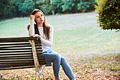 Thoughtful young woman sitting on bench in park