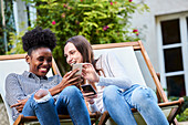 Lächelnde junge Freunde, die Smartphones im Park benutzen