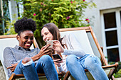 Smiling young friends using smartphones in park