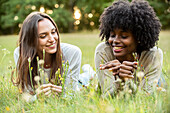 Lächelnde junge Freundinnen im Park liegend