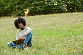 Smiling young woman using digital tablet in public park