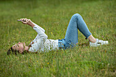 Young woman using smart phone while lying in park